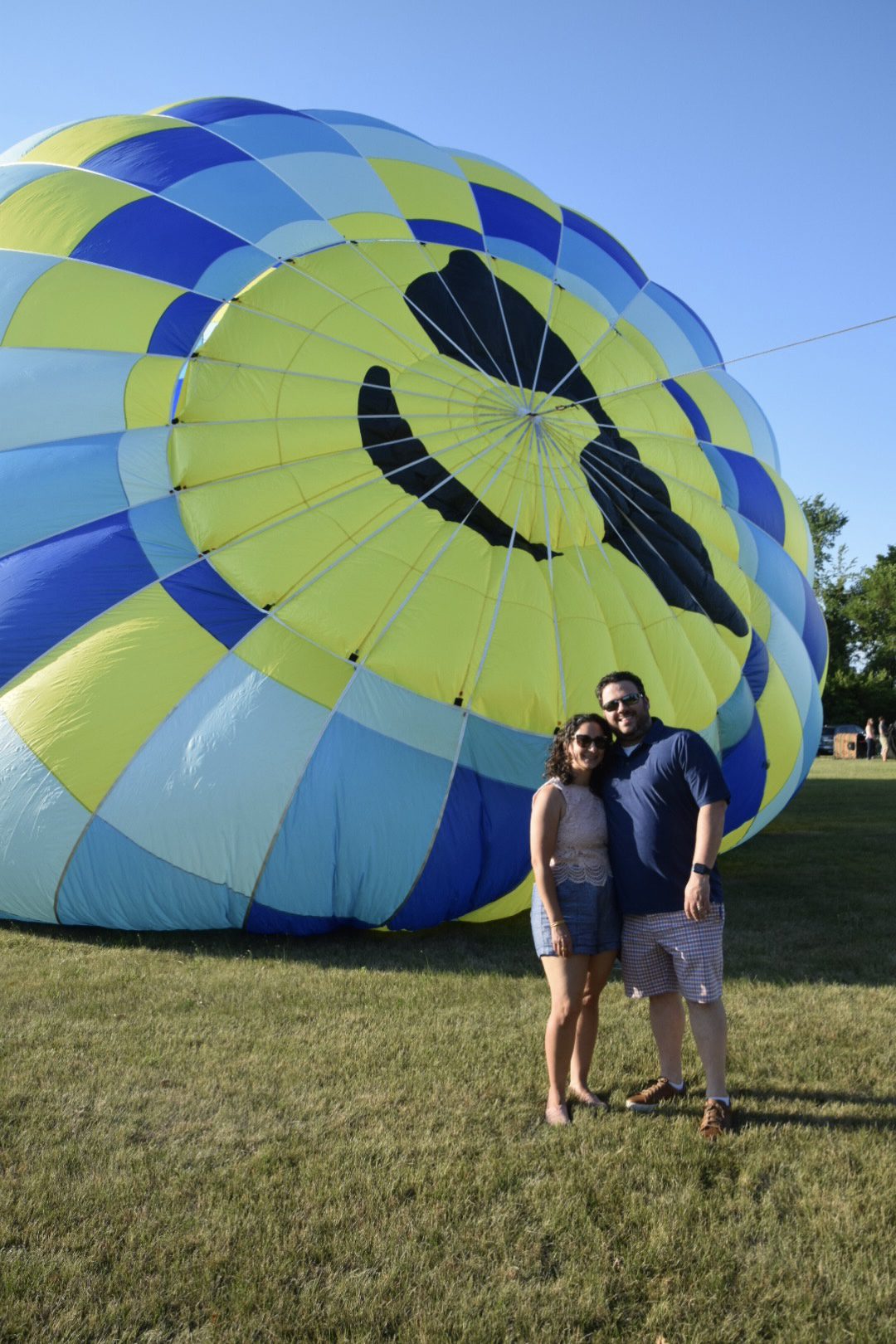 Couple standing before colorful hot air balloon