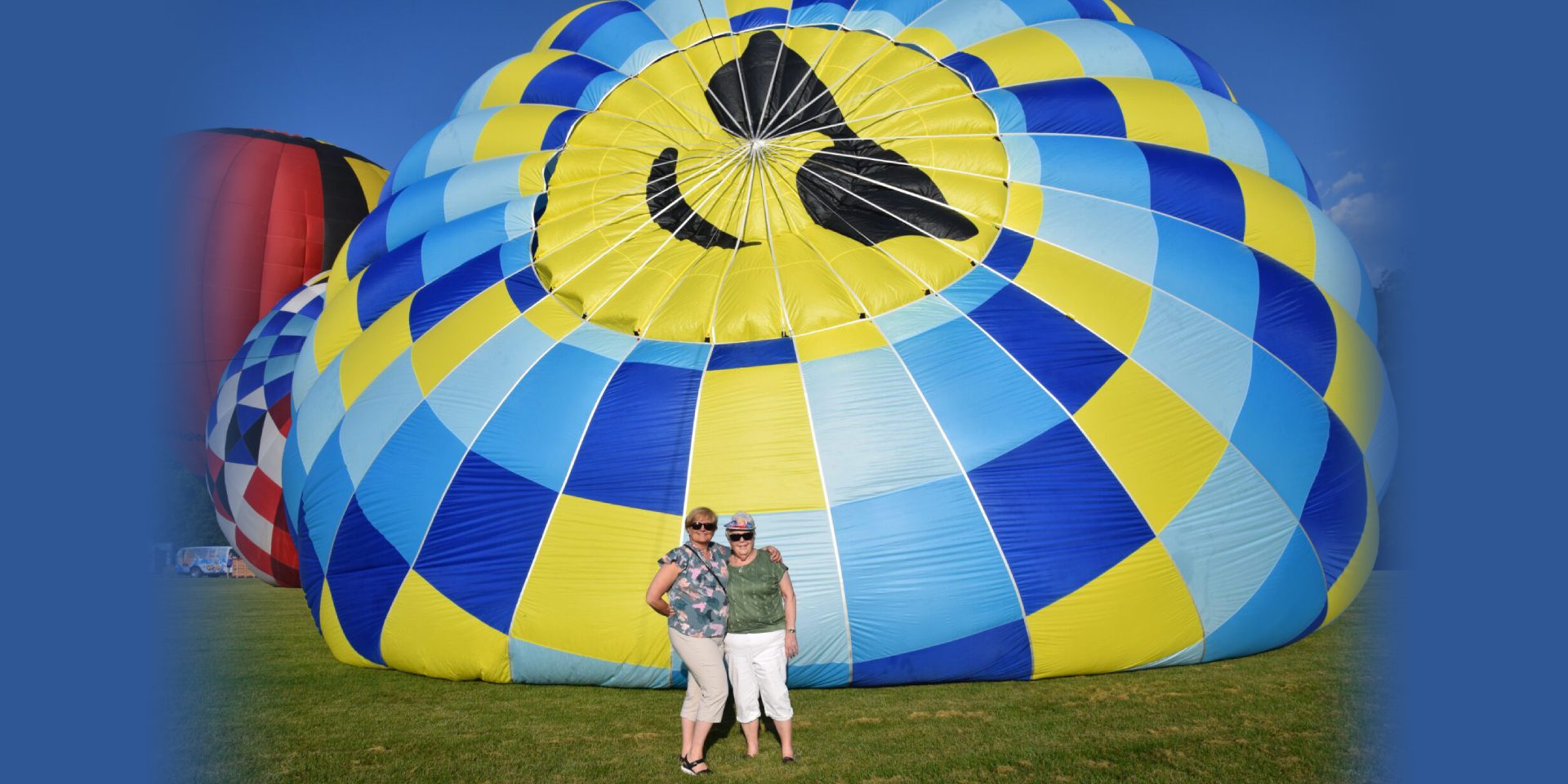 Two people standing by colorful hot-air balloon