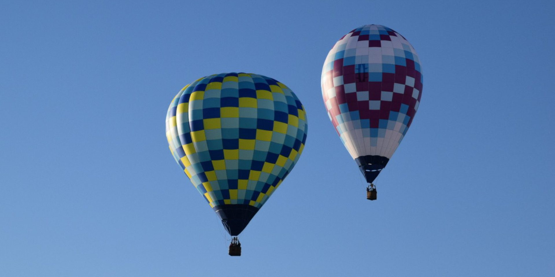 Two colorful hot air balloons against blue sky
